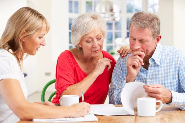 A middle-aged couple reviewing legal documents with a professional woman at a table, representing a family law consultation with Nussbaum family lawyers in Toronto.