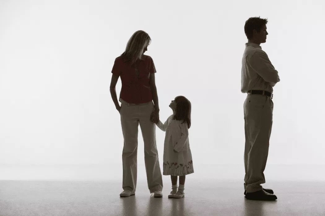 Silhouetted image of a mother holding her daughter's hand while the father stands apart with arms crossed, symbolizing family separation and the need for legal support from Nussbaum family lawyers in Toronto.