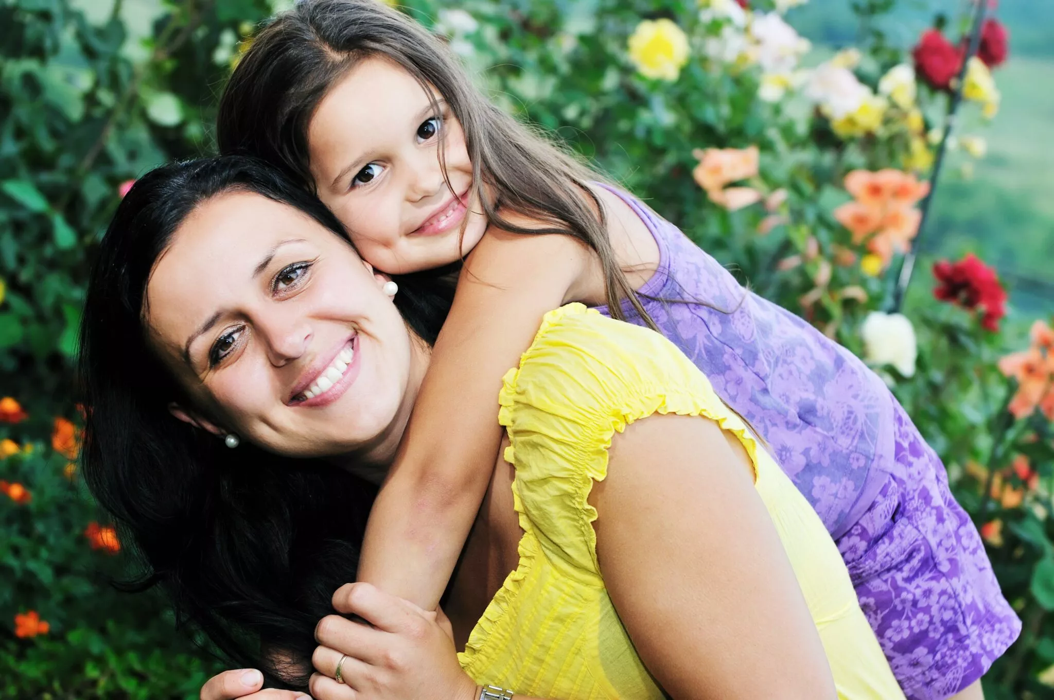 Smiling mother and daughter embracing outdoors surrounded by colorful flowers, symbolizing family unity and support relevant to Nussbaum family lawyers in Toronto