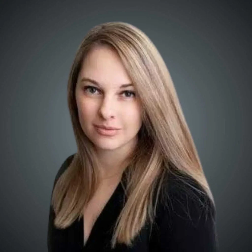 Portrait of a woman with long blonde hair wearing a black top against a dark gray background