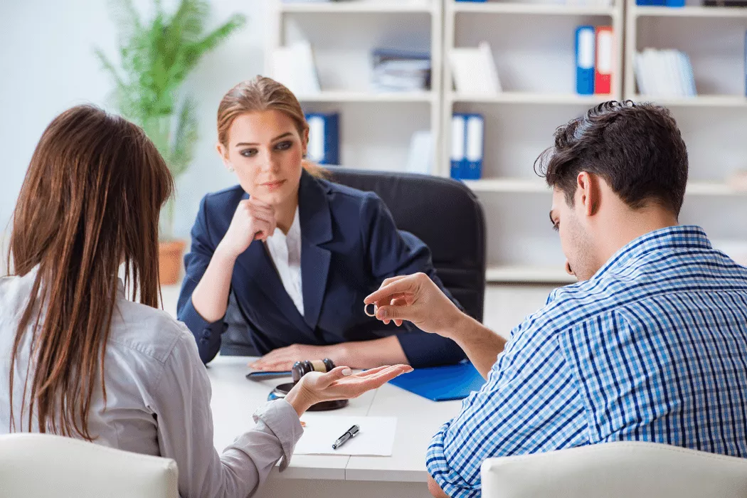 Couple consulting with a female family lawyer in a modern office, discussing the exchange of a wedding ring, representing Nussbaum family lawyers in Toronto.