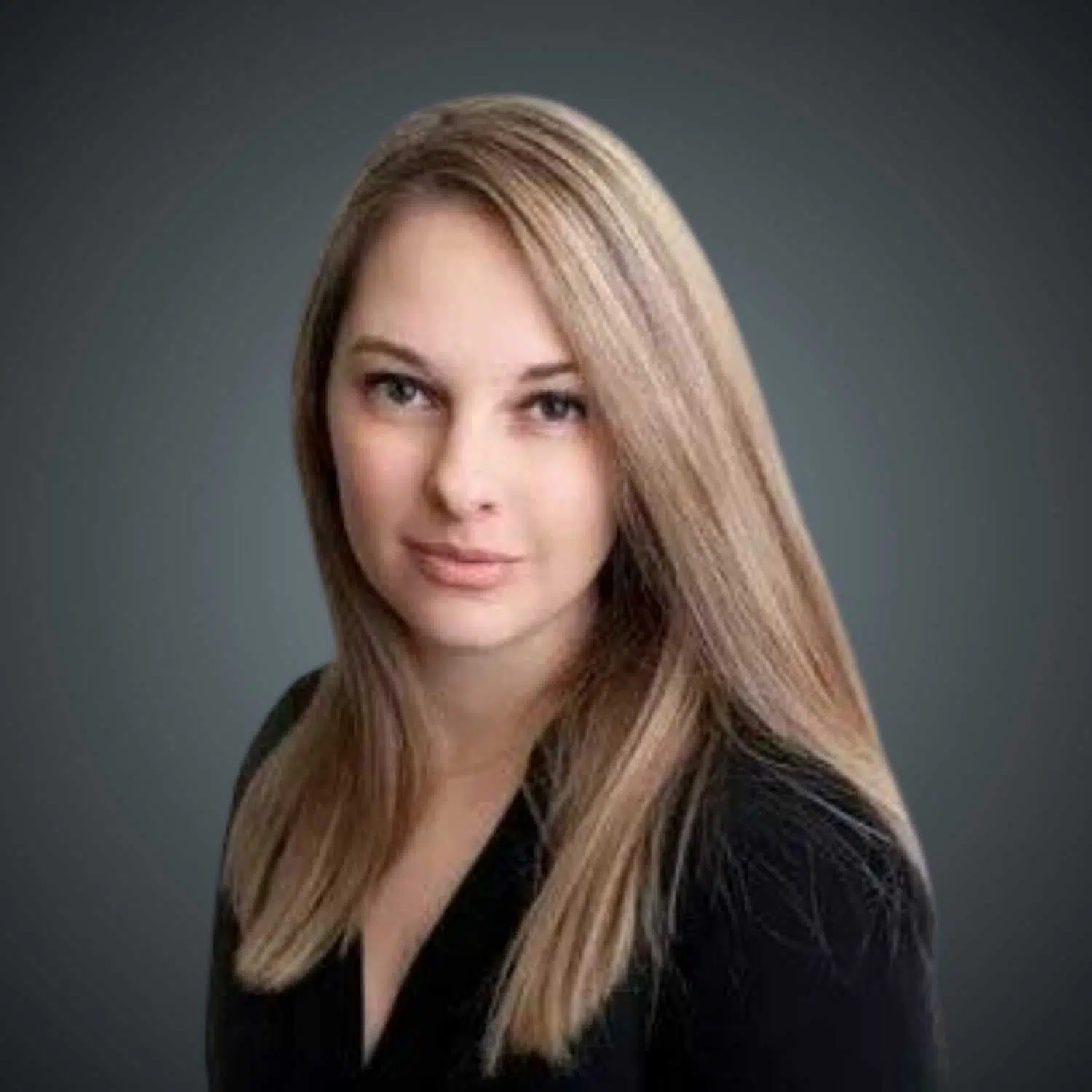 Portrait of a woman with long blonde hair wearing a black top against a dark gray background