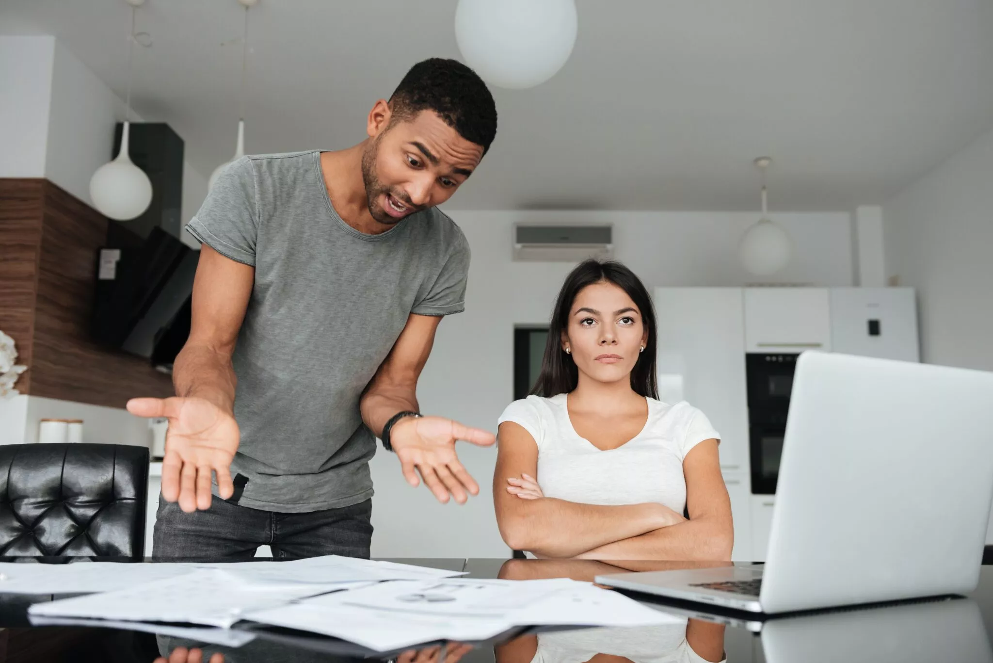 Frustrated couple sitting at a table with scattered documents and a laptop, possibly discussing family legal matters, symbolizing issues addressed by Nussbaum family lawyers in Toronto.