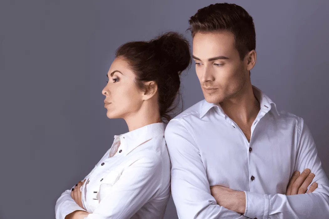 A serious man and woman standing back to back with arms crossed, symbolizing a couple facing family legal issues, suitable for Nussbaum Family Lawyers in Toronto.